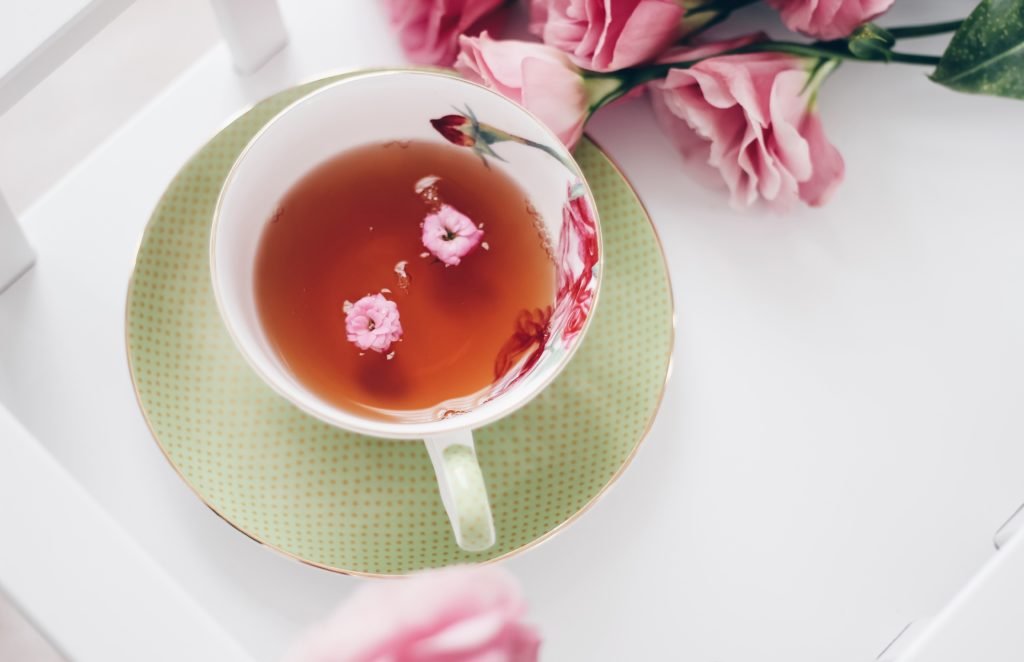 Infusion de thé avec des rose à côté de la tasse.