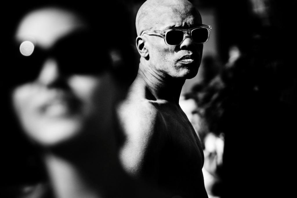 Un homme avec des lunettes de soleil se distingue de la foule en regardant l'objectif