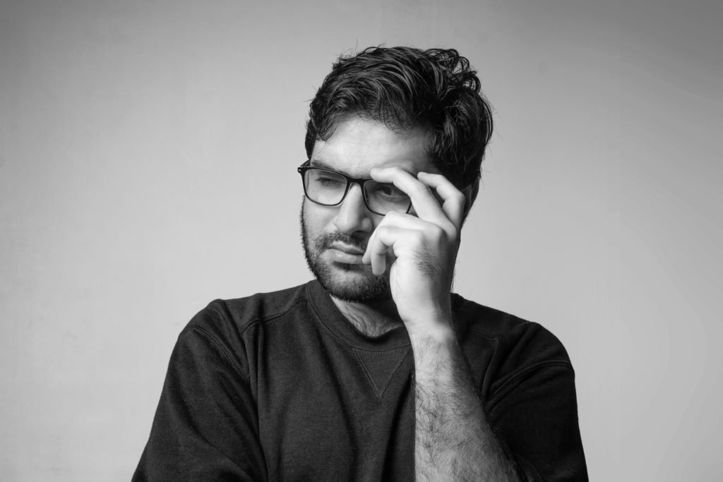 Un homme pensif tient ses lunettes de la main gauche